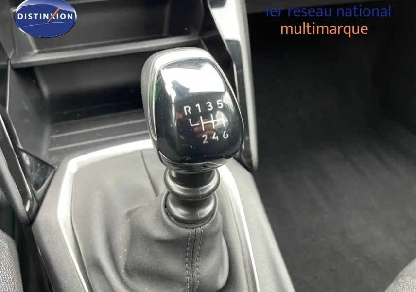 Le levier de vitesses manuel de la Peugeot 208 gris Artense, vu en gros plan depuis l'avant intérieur.