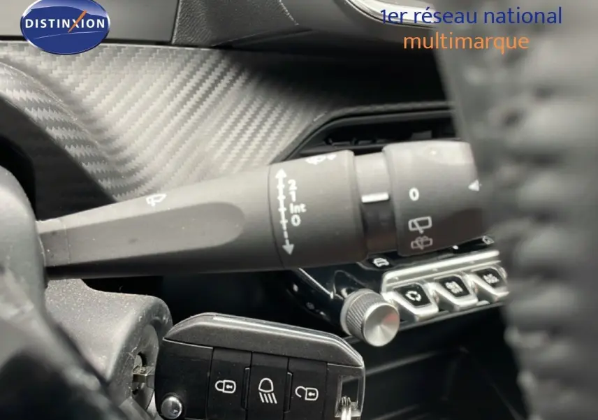 Gros plan sur la commande d'essuie-glace et les boutons de réglage, intérieur noir avec finition carbone du Peugeot 208 gris.