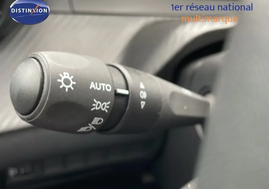 Gros plan sur la commande des feux au volant d’une Peugeot 208 gris Artense, version 2025, intérieur noir.