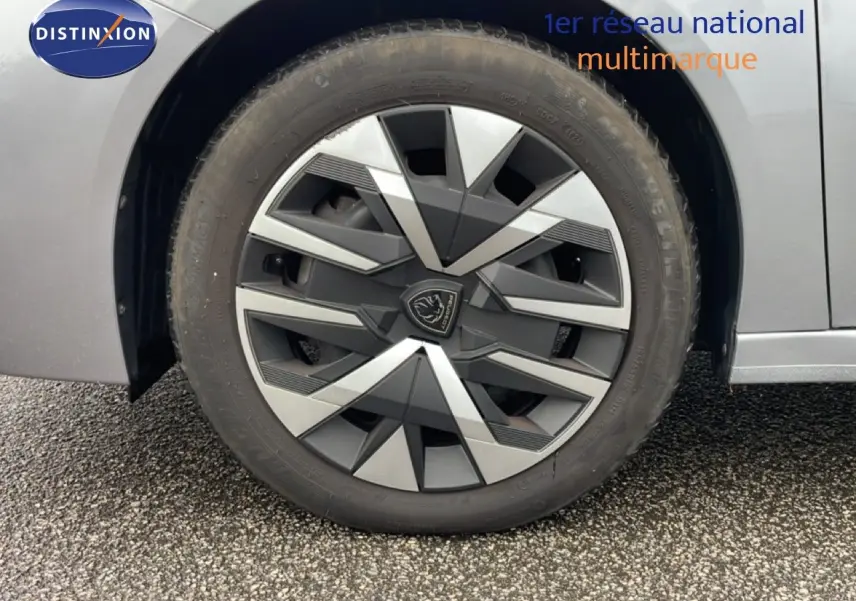 Gros plan sur la roue avant droite d’une Peugeot 208 gris Artense métal, mettant en valeur la jante au design géométrique.