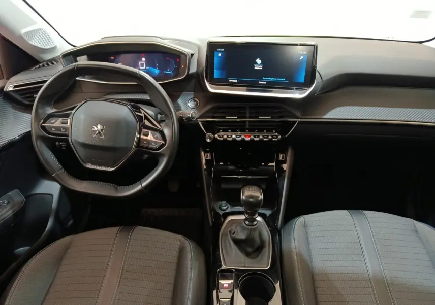 Vue intérieure avant de la Peugeot 208 PureTech 100 blanche, volant cuir, écran tactile 10 pouces et boîte manuelle.