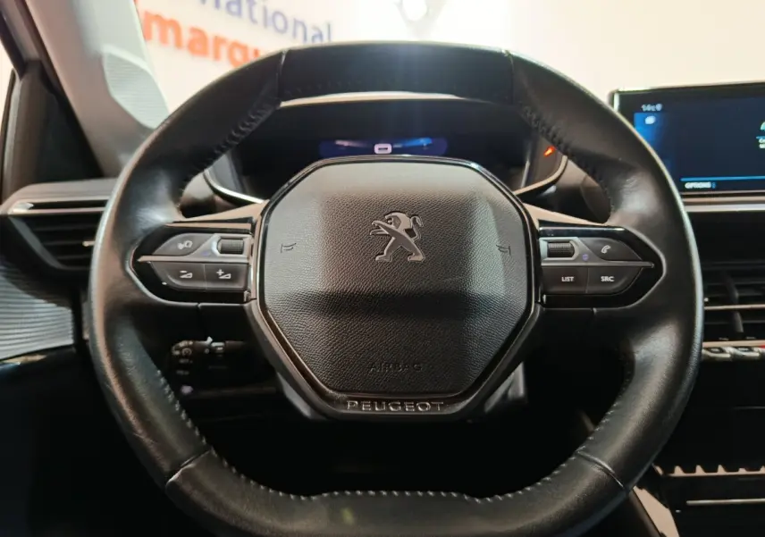 Gros plan sur le volant cuir multifonctions noir de la Peugeot 208 PureTech 100 S&S Allure Business 2021.