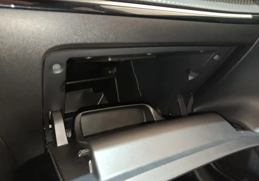 Vue rapprochée de la boîte à gants ouverte côté passager du Peugeot 208 blanc, intérieur noir.