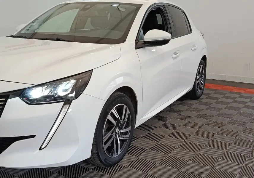 Peugeot 208 blanc vue 3/4 avant droit avec phares LED allumés et jantes alliage noires.