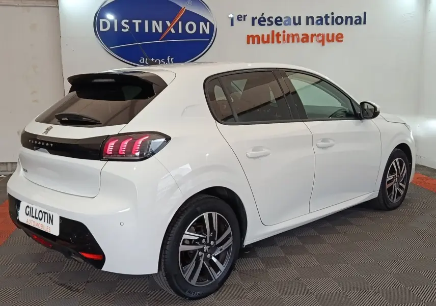 Vue 3/4 arrière droite d'une Peugeot 208 blanche avec feux arrière LED et jantes alliage bicolores.