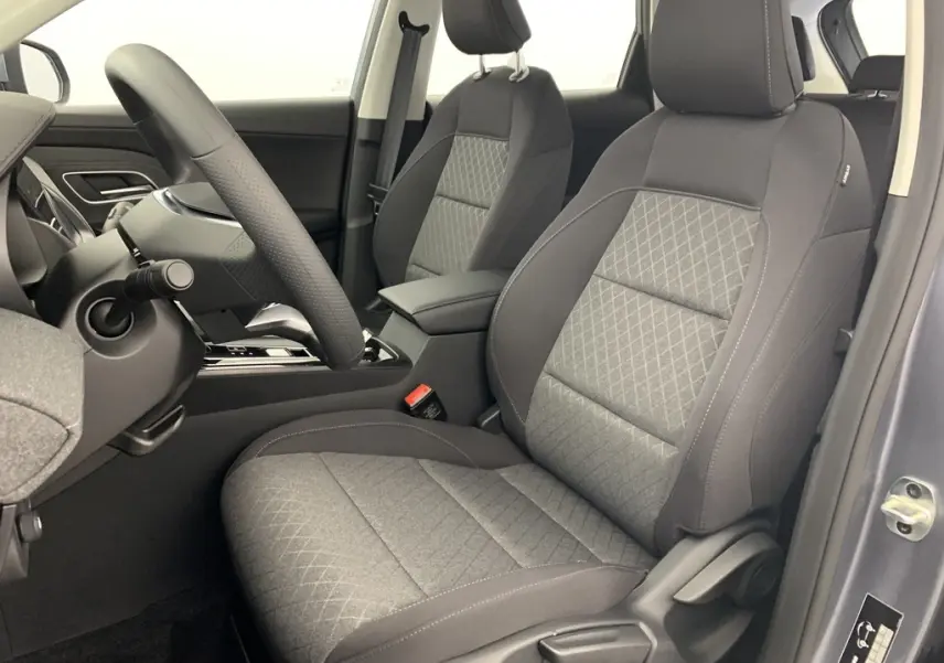 Vue intérieure côté conducteur du MG ZS 2026 avec sièges en tissu noir et gris, volant et console centrale visibles.