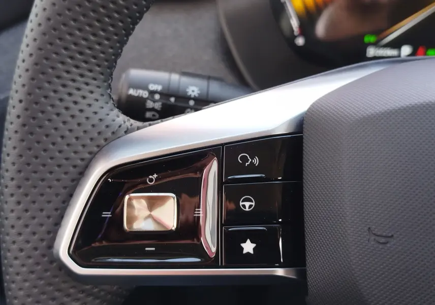 Gros plan sur les commandes multifonctions à gauche du volant perforé du MG ZS 2026 en couleur Hampstead Grey.