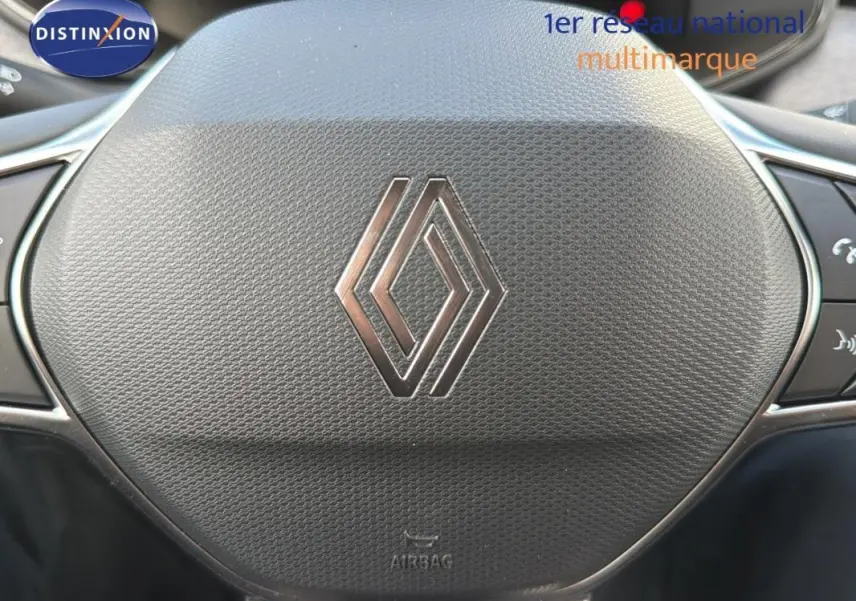 Gros plan sur le volant noir avec logo Renault de la Clio gris foncé, version 2026, montrant les commandes intégrées.