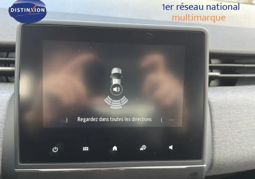 Écran tactile intérieur de la Renault Clio gris foncé 2026 affichant l'aide au stationnement avec message de vigilance.