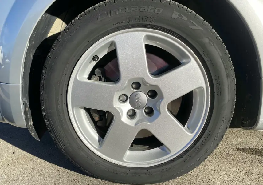 Gros plan sur la roue avant gauche grise de l'Audi TT Coupé (8N) avec jante alliage cinq branches.