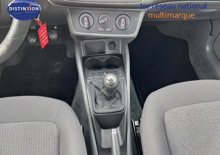 Vue intérieure centrée sur la console centrale d'une SEAT Ibiza blanche 2010 avec levier de vitesse manuel et commandes climatiques.