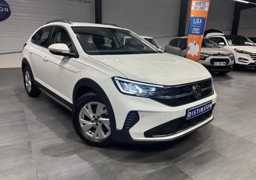 Volkswagen Taigo blanc en 3/4 avant droit, avec jantes alliage et calandre noire brillante en showroom.