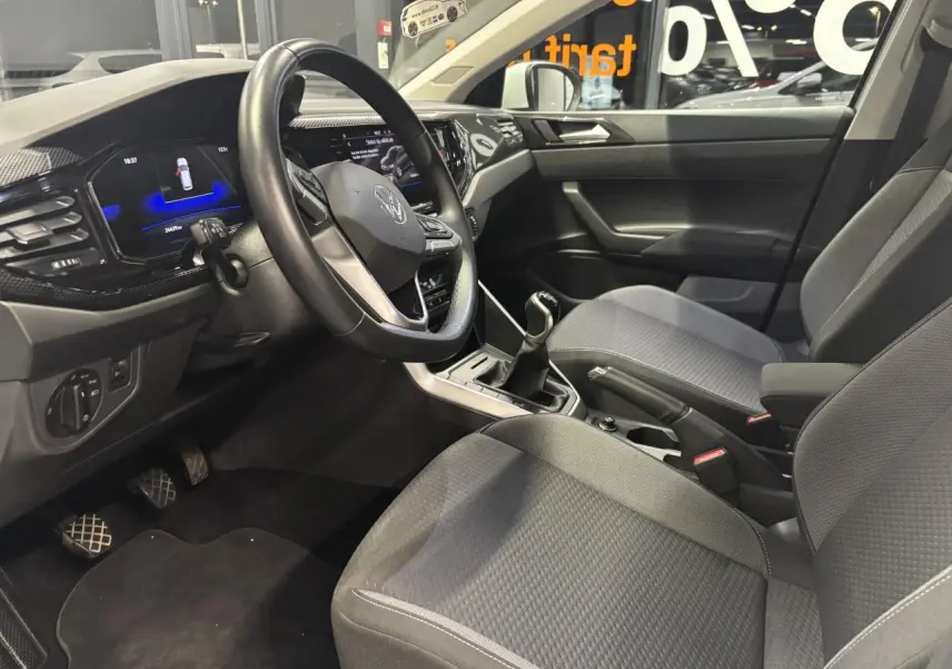 Vue intérieure côté conducteur du Volkswagen Taigo 1.0 TSI 2023, montrant le volant cuir multifonctions et la sellerie tissu grise.