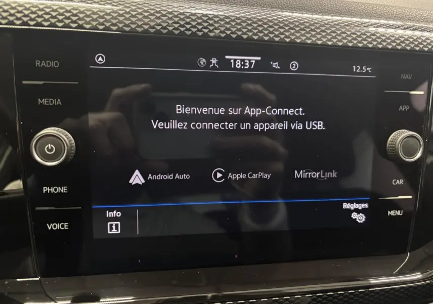 Écran tactile central du Volkswagen Taigo blanc 2023 affichant l'interface App-Connect avec commandes autour.