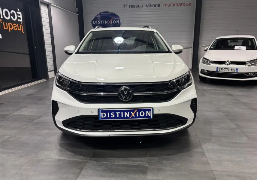 Vue de face du Volkswagen Taigo blanc avec calandre noire et logo VW central dans un showroom.