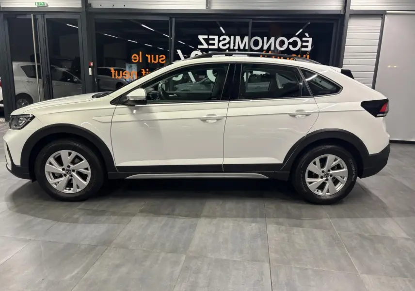 Vue latérale droite d’un Volkswagen Taigo blanc 2023 avec jantes alliage et protections noires sur les passages de roues.