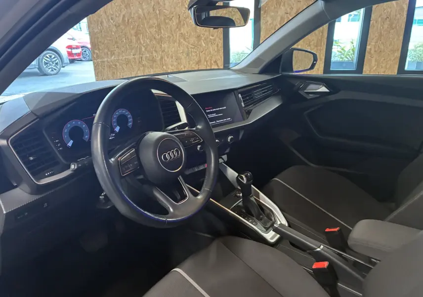 Intérieur noir de l'Audi A1 2022 vu côté conducteur, volant cuir multifonctions et tableau de bord numérique.