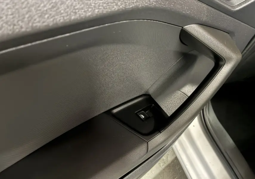 Gros plan sur la commande de lève-vitre côté gauche d’une Audi A1 blanche, intérieur noir texturé.
