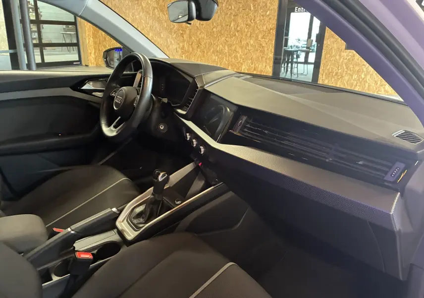 Intérieur noir de l'Audi A1 2022 vu côté conducteur, avec volant cuir multifonctions et console centrale moderne.