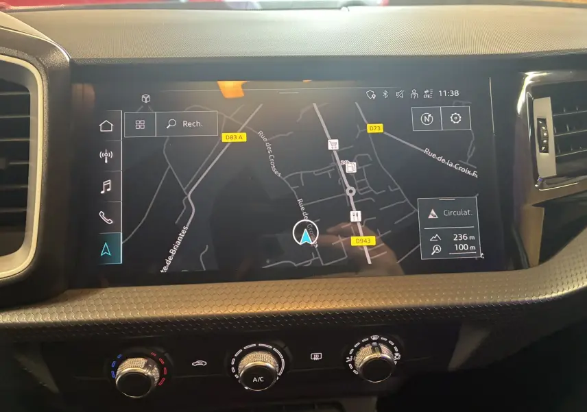 Vue rapprochée de l'écran GPS tactile et des commandes de climatisation de l'Audi A1 blanche de 2022.