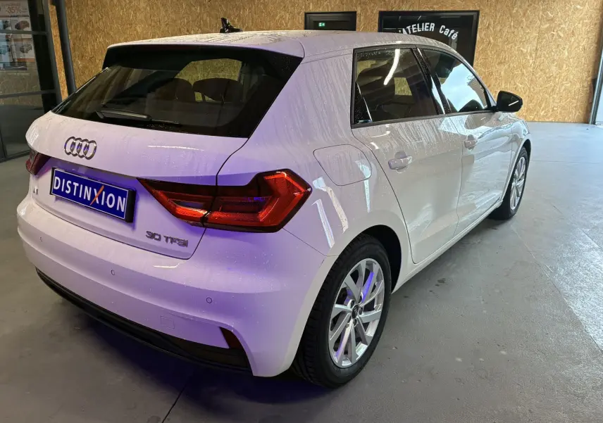 Vue 3/4 arrière droite d'une Audi A1 blanche 2022 avec jantes alu 17 pouces et feux arrière LED dans un garage.