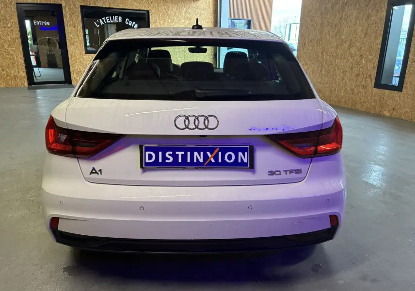 Vue arrière d'une Audi A1 blanche 30 TFSI avec feux LED et capteurs de stationnement visibles en intérieur.