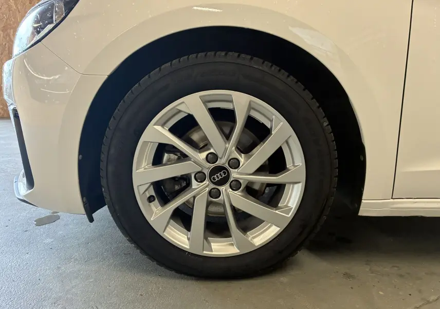 Gros plan sur la roue avant gauche d'une Audi A1 blanche avec jante alu 17 pouces au design moderne.