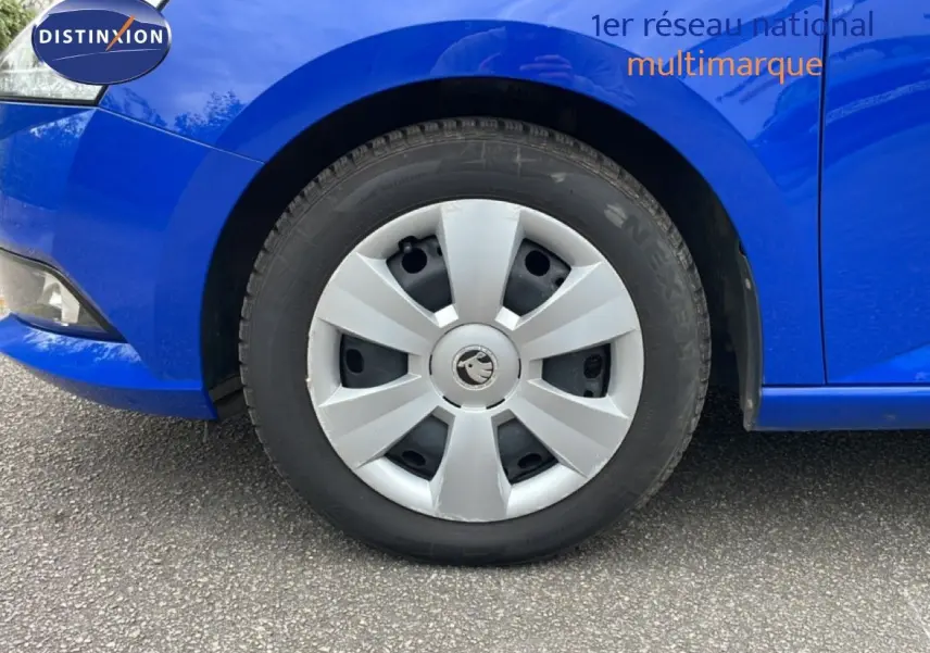 Gros plan sur la roue avant droite d'une Skoda Fabia bleu énergie, mettant en valeur la jante en plastique gris clair.