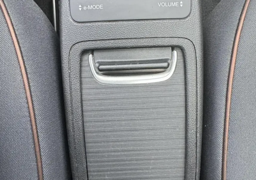 Vue rapprochée de la console centrale noire entre les sièges gris anthracite de la Fiat 500 électrique blanche.