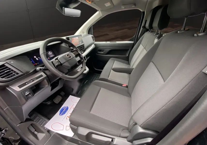 Intérieur avant de l'Opel Vivaro noir 2025, vue côté conducteur montrant sièges tissu gris et tableau de bord moderne.