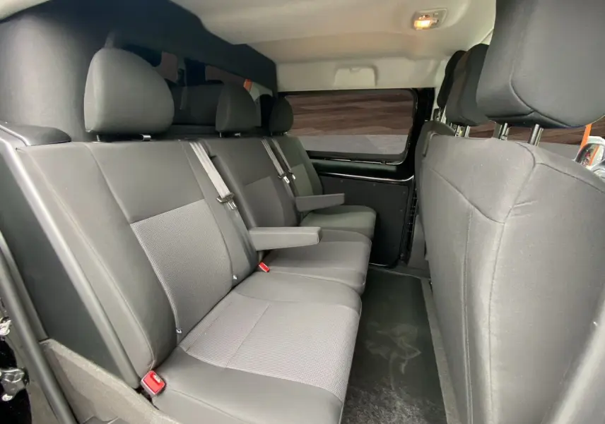 Vue intérieure côté droit des sièges arrière noirs en tissu du fourgon Opel Vivaro 2025 avec accoudoirs et ceintures de sécurité.