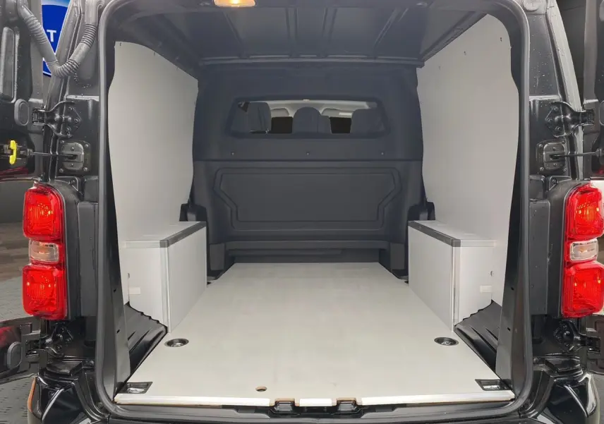 Vue arrière de l’intérieur noir et bois clair du fourgon Opel Vivaro 2025 avec plancher et habillage latéral en bois.