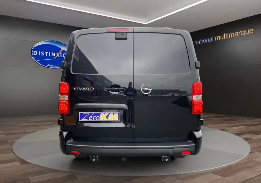 Vue arrière d'un Opel Vivaro noir avec attelage et feux arrière rouges dans un showroom.