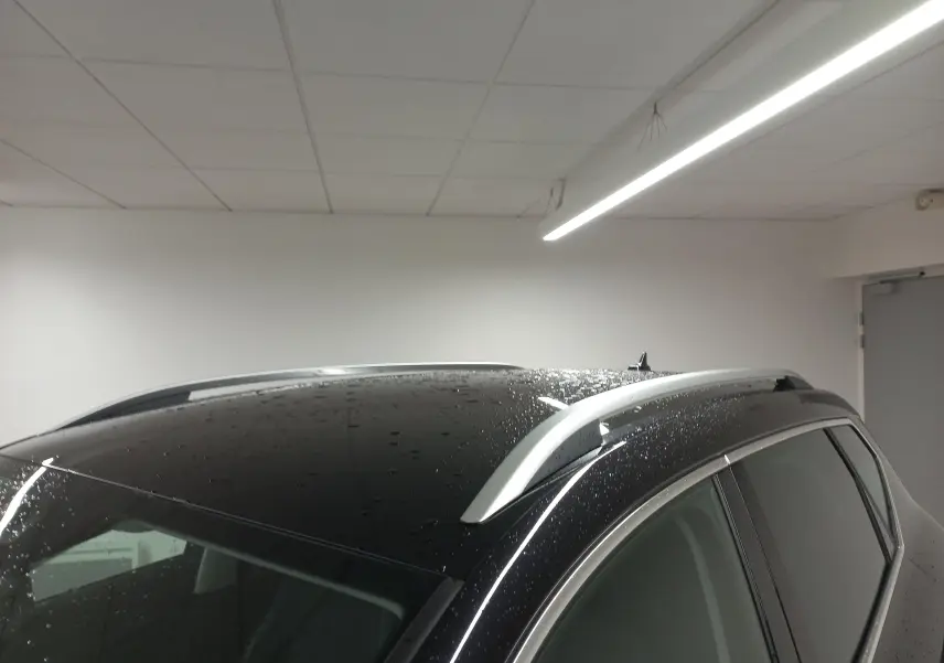 Toit noir nacré du SEAT Ateca 2.0 TDI 150 DSG7 Copa avec barres de toit argentées, vue latérale droite en intérieur.