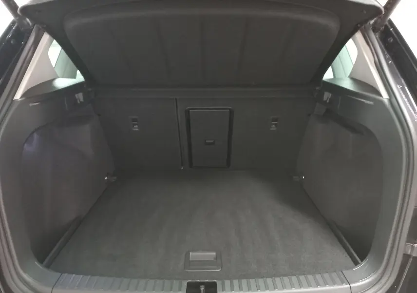Coffre ouvert du SEAT Ateca noir Magic Nacré, vue arrière montrant l'espace de chargement vide et la trappe centrale.
