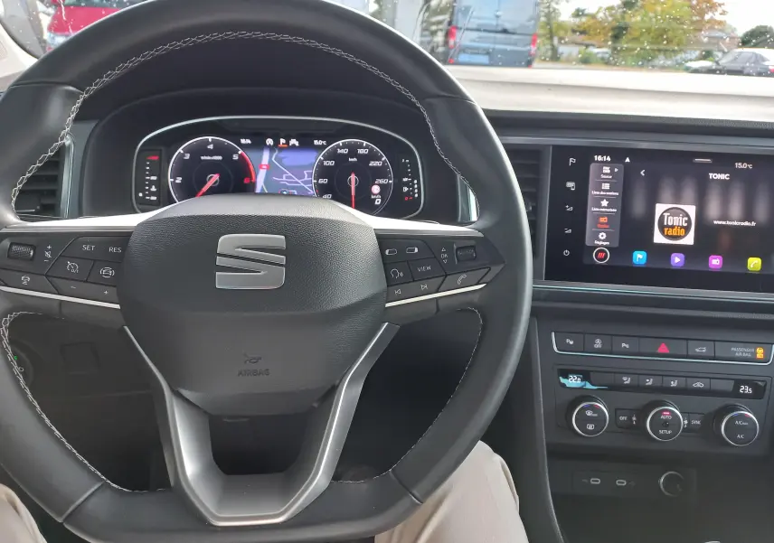 Vue intérieure centrée sur le volant et le tableau de bord numérique d'un SEAT Ateca 2.0 TDI noir, avec écran tactile multimédia.