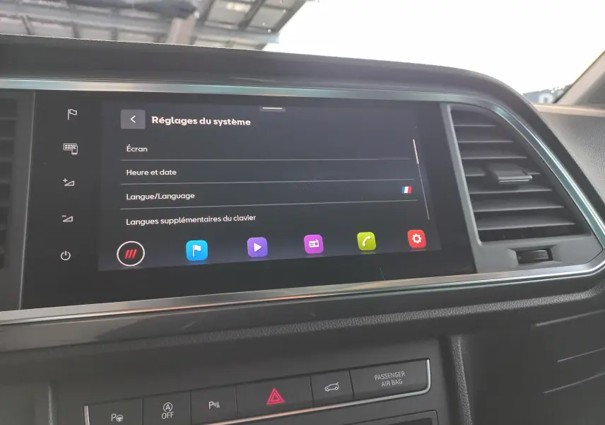 Écran tactile central du tableau de bord du SEAT Ateca 2025 avec réglages système affichés, entouré de commandes et aérateurs.
