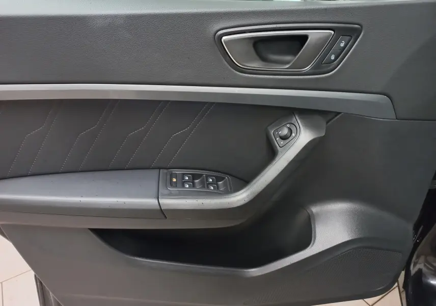 Gros plan sur la porte intérieure côté gauche du SEAT Ateca noir, avec commandes de vitres et verrouillage intégrés.