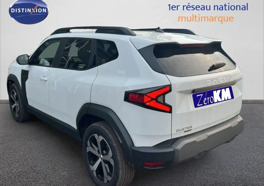 Vue 3/4 arrière droite du Dacia Duster Hybrid 140 blanc Glacier avec jantes alliage 18 pouces et barres de toit.