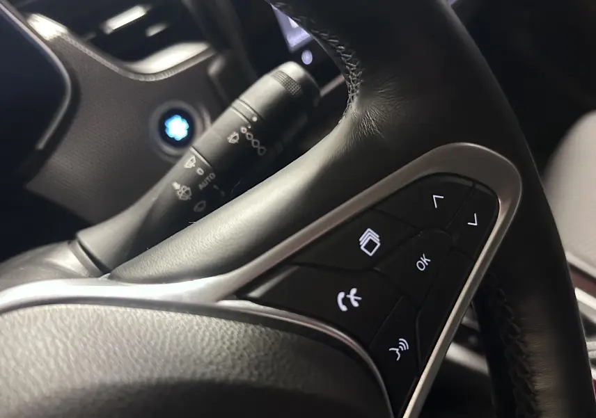 Gros plan sur les commandes au volant noir du Renault Arkana 1.6 E-Tech 145ch Intens, avec boutons multifonctions éclairés.