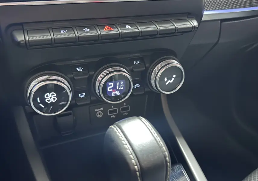Gros plan sur la console centrale noire du Renault Arkana 1.6 E-Tech, avec commandes climatisation et levier de boîte auto.