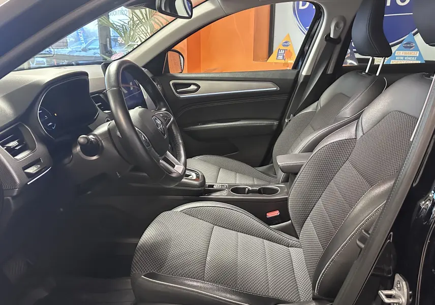 Vue intérieure côté conducteur du Renault Arkana noir 2022, montrant sièges tissu et cuir avec tableau de bord moderne.