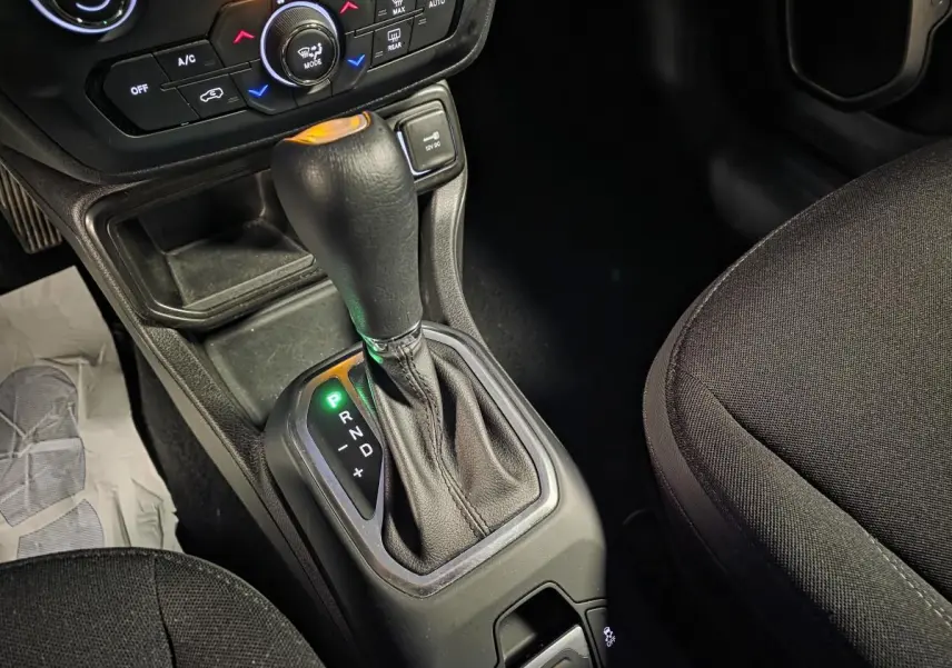 Le levier de vitesse automatique noir du Jeep Renegade 2024 en vue rapprochée côté droit, avec console et sièges tissus.