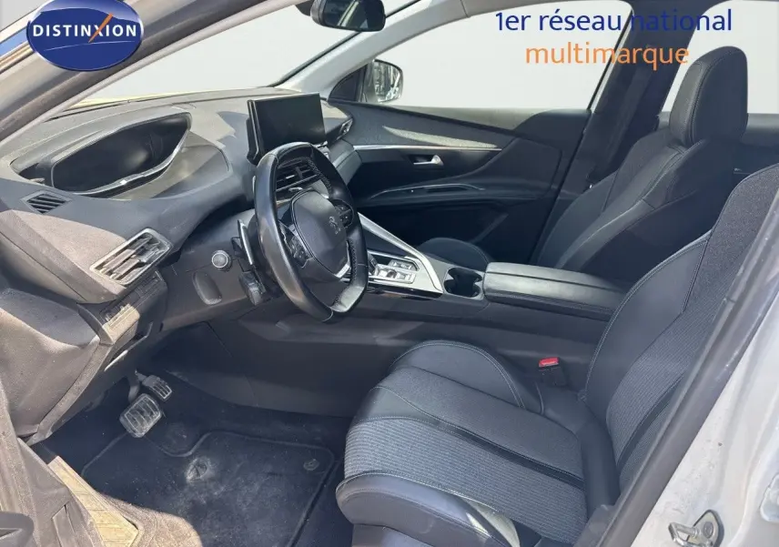 Vue intérieure côté conducteur du Peugeot 3008 blanc nacré 2022, avec sièges noirs en cuir et tableau de bord moderne.