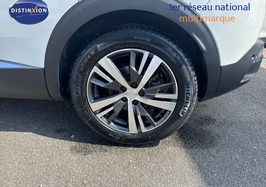 Gros plan sur la roue arrière droite d’un Peugeot 3008 blanc nacré avec jante alliage bicolore et pneu Michelin.