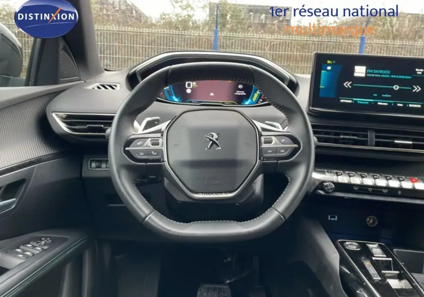 Vue intérieure centrée sur le volant cuir multifonction et le tableau de bord numérique du Peugeot 3008 gris Artense 2024.