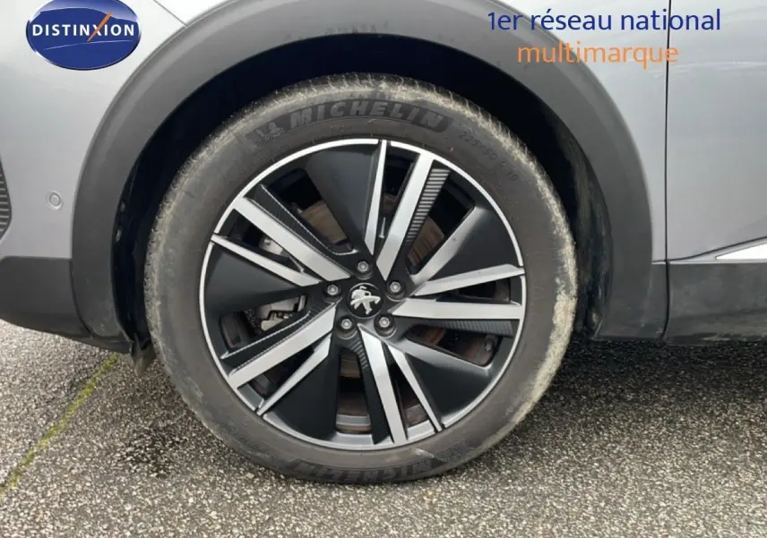 Gros plan sur la roue avant gauche d’un Peugeot 3008 gris Artense avec jante alliage bicolore 19 pouces.