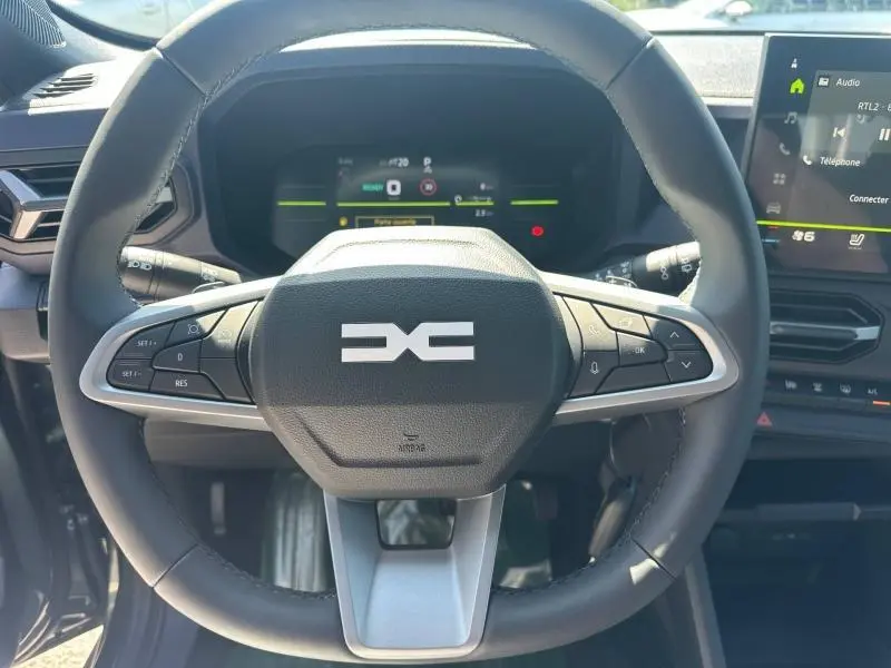 Vue rapprochée du volant multifonction noir du Dacia Duster 2026, avec tableau de bord numérique et écran tactile visible.
