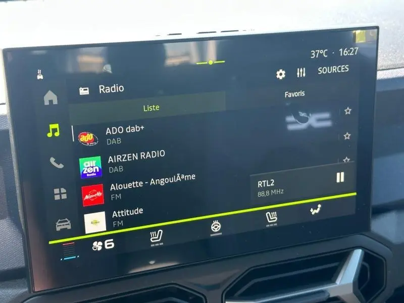Écran tactile central du Dacia Duster 2026 affichant les radios DAB et FM avec commandes climatisation en bas.