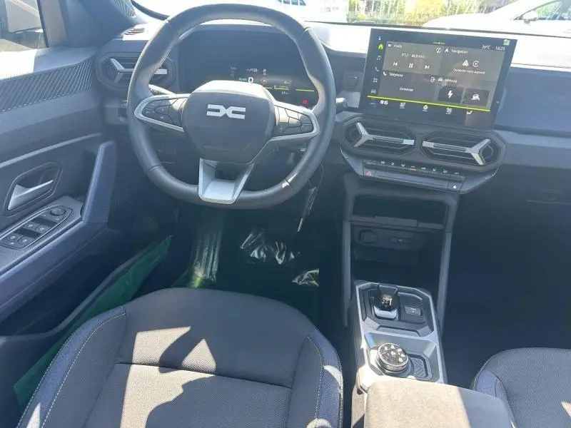 Vue intérieure avant du tableau de bord du Dacia Duster 1.2 hybrid-G 150ch Expression 4x4 avec volant multifonction et écran tactile.